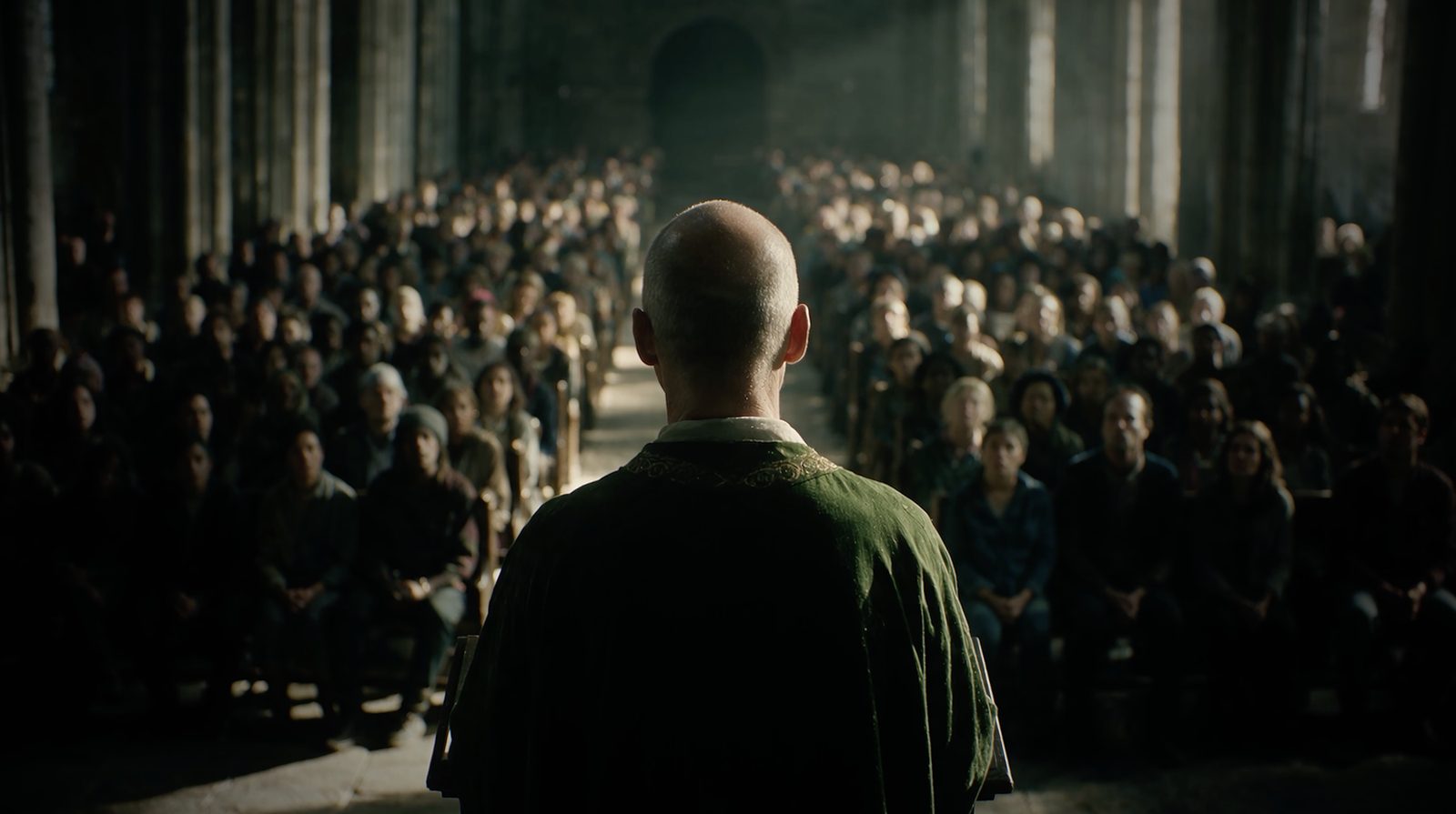 A priest seen from behind, facing a full congregation in a cathedral nave.